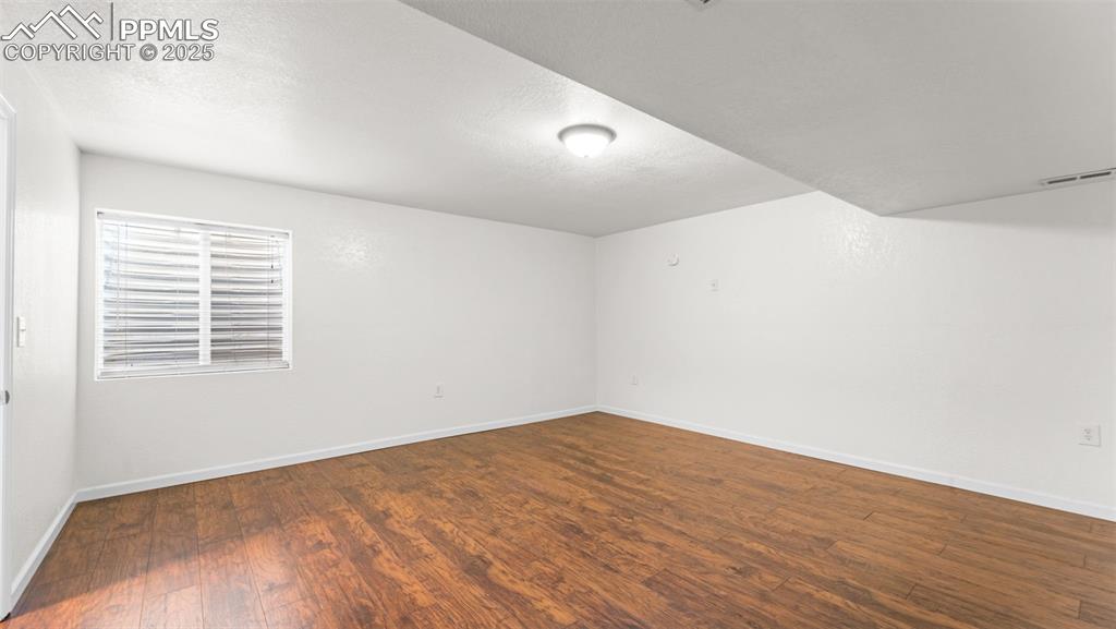 Image 9 of 50: Basement room featuring dark wood-style flooring and a textured ceiling
