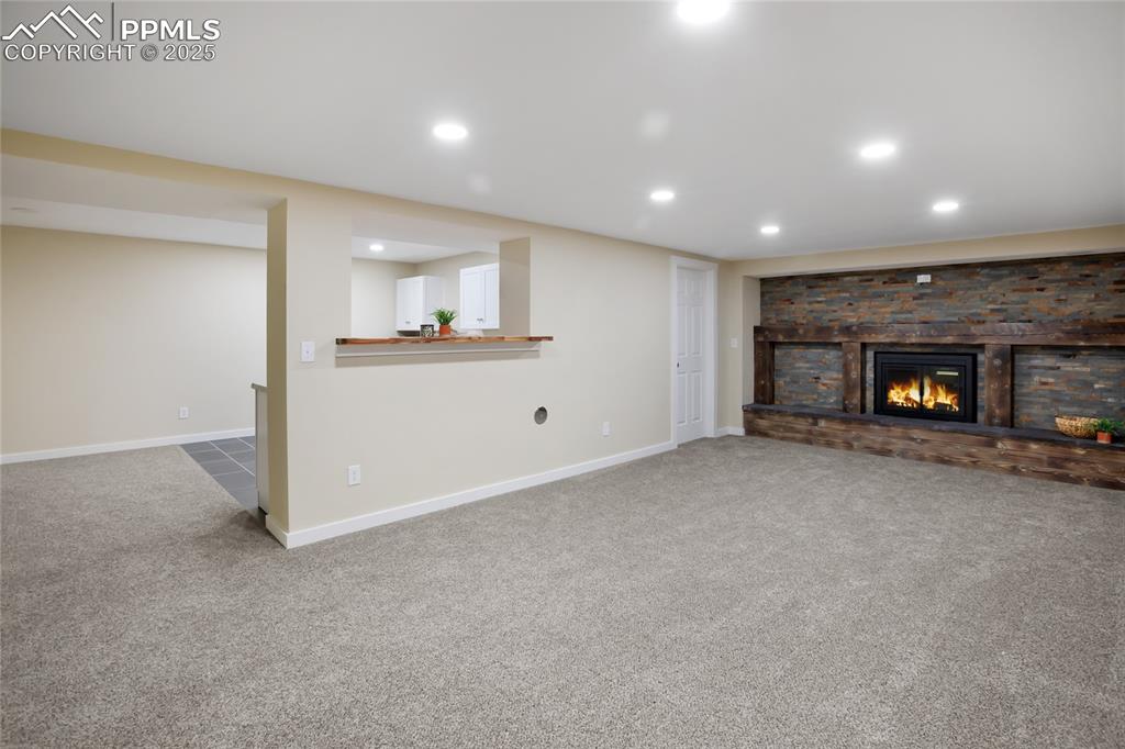 Image 21 of 37: Open concept lower level with floor to ceiling fireplace.