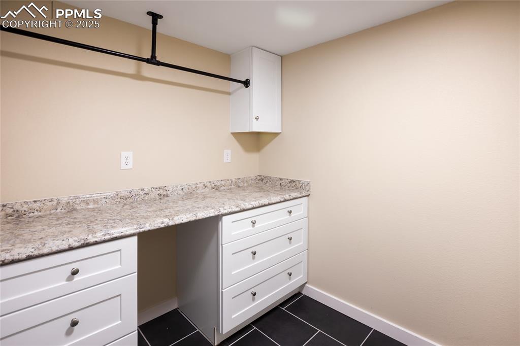 Image 22 of 37: Lower level laundry room with cabinet space and laundry rod