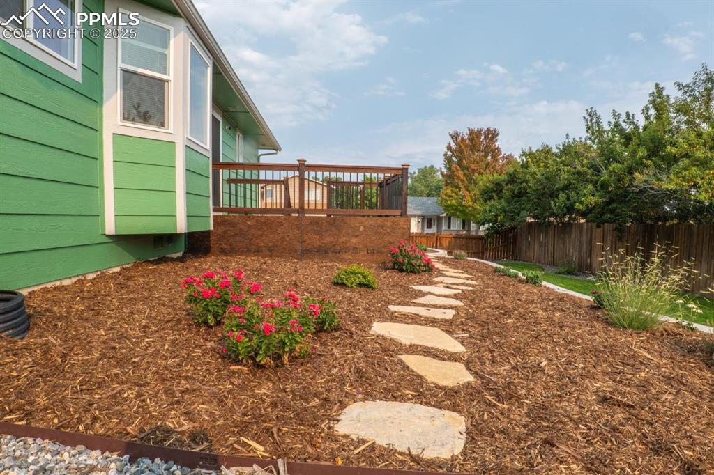Image 24 of 26: Lovely landscaping in the backyard to include rock, mulch, grass and a pop 