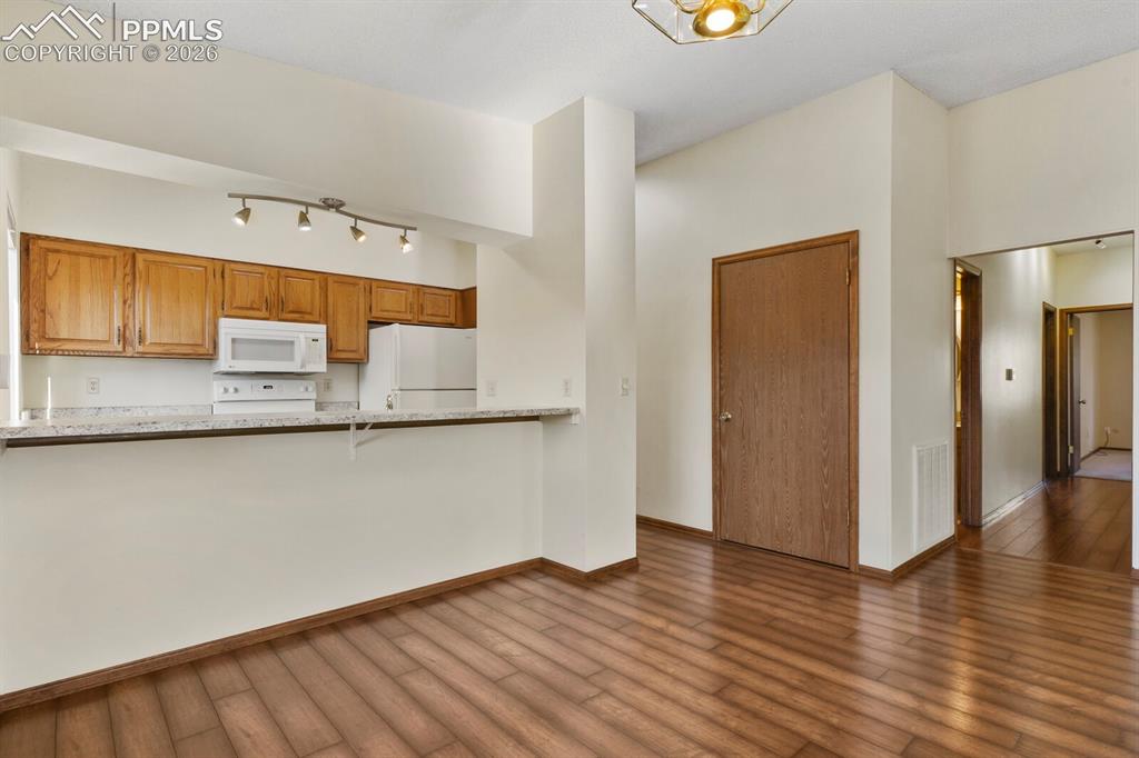 Image 10 of 27: Kitchen bar with light wood cabinetry, white appliances, and a light-toned 