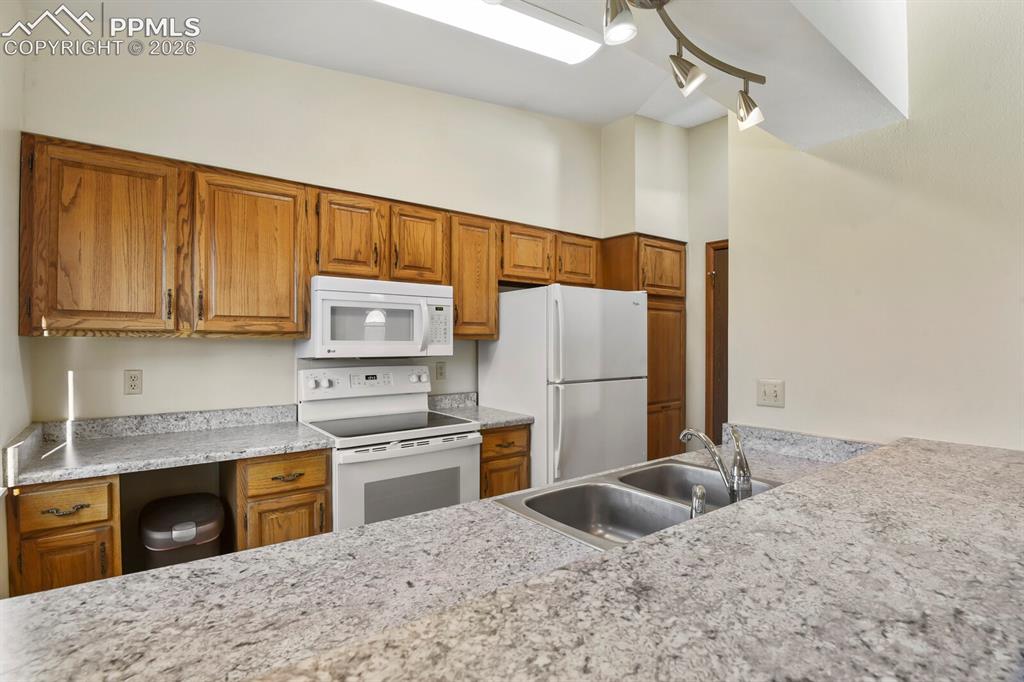 Image 11 of 27: Kitchen featuring light-toned wood cabinetry with brass hardware, white app