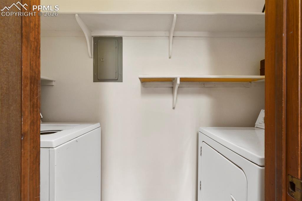 Image 16 of 27: Dedicated laundry area featuring white walls, open shelving, and a visible 