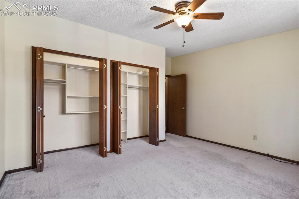 Image 21 of 27: Bedroom featuring two bifold door closets with built-in shelving, light-col