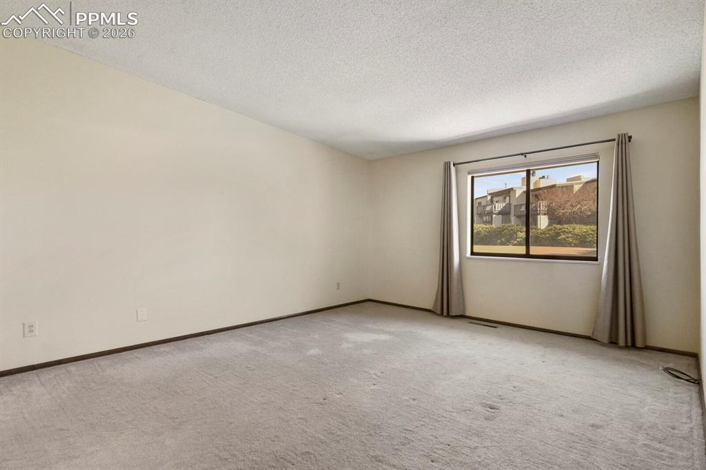 Image 22 of 27: Spacious room featuring neutral carpeting, light-colored wall paint, and a 