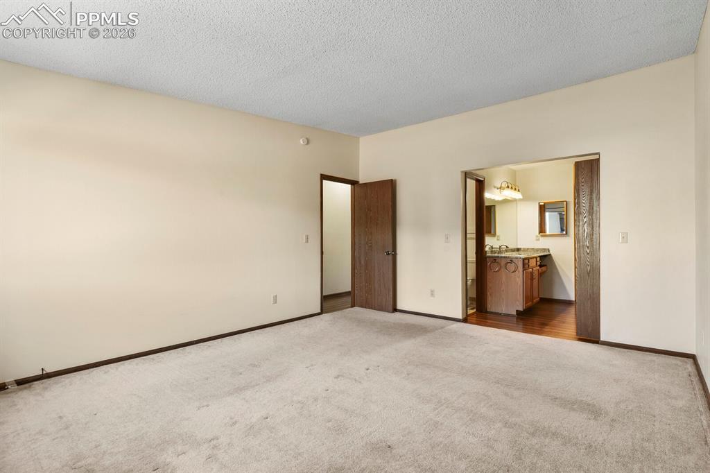 Image 23 of 27: Spacious carpeted room featuring light-toned walls, a textured ceiling, and