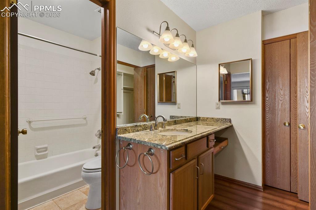 Image 24 of 27: Bathroom featuring a wood-finish vanity with a built-in sink, stone-finish 