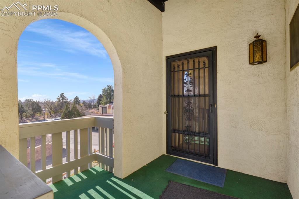 Image 4 of 27: Archway entrance featuring a wrought iron security door, stucco exterior fi