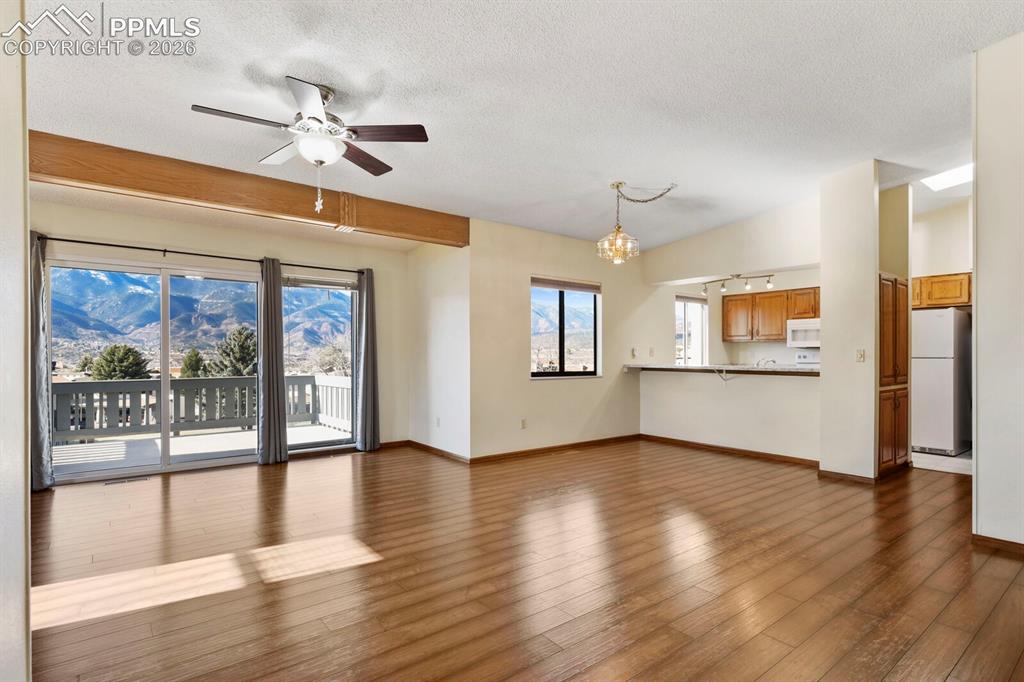 Image 5 of 27: Expansive living area with wood-finish flooring, a ceiling fan, and a wood 