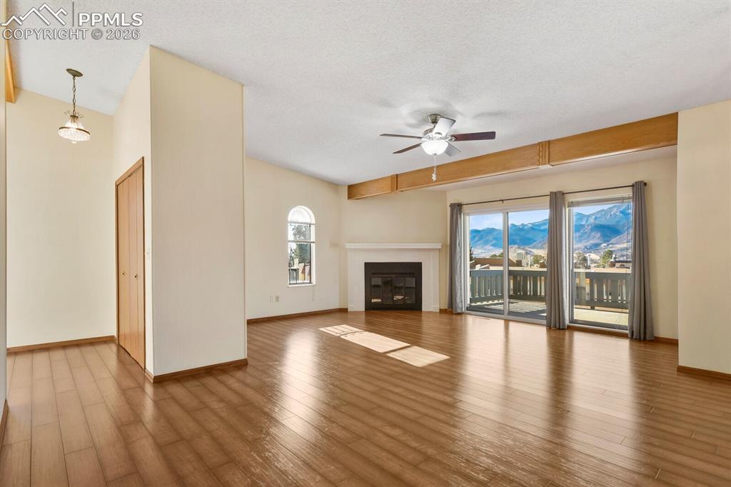 Image 6 of 27: Spacious living area featuring expansive wood-finish flooring and a vaulted