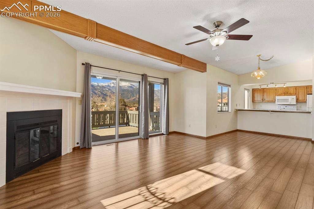 Image 7 of 27: Open-concept living area with wood-finish flooring, vaulted ceilings, and e