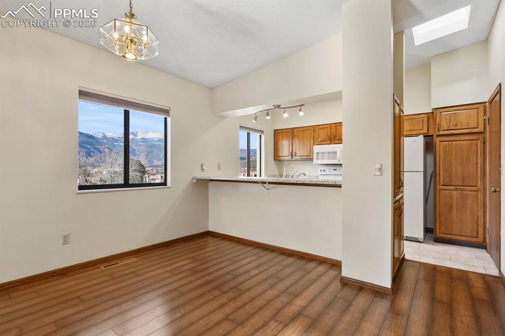 Image 9 of 27: Open-concept dining area featuring wood-finish flooring, a contemporary cei