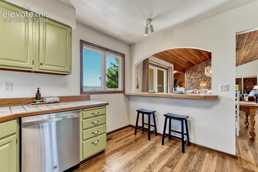 Image 15 of 50: Kitchen features counter bartop, pantry, stainless steel appliances, and pa