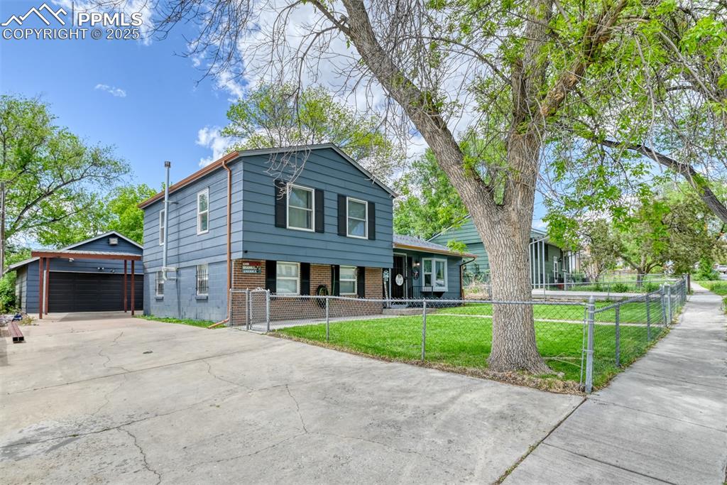 Caption: View of front of property featuring brick siding, an outdoor structure, a garage, and a fenced front