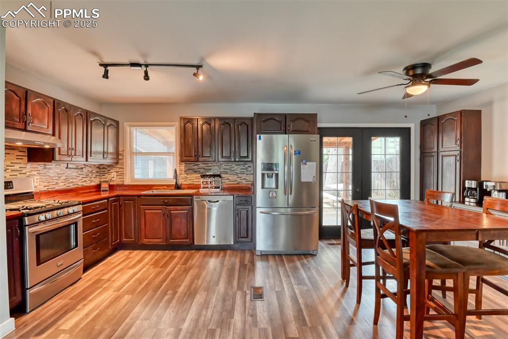 Image 15 of 37: Kitchen with stainless steel appliances, tasteful backsplash, light wood fi