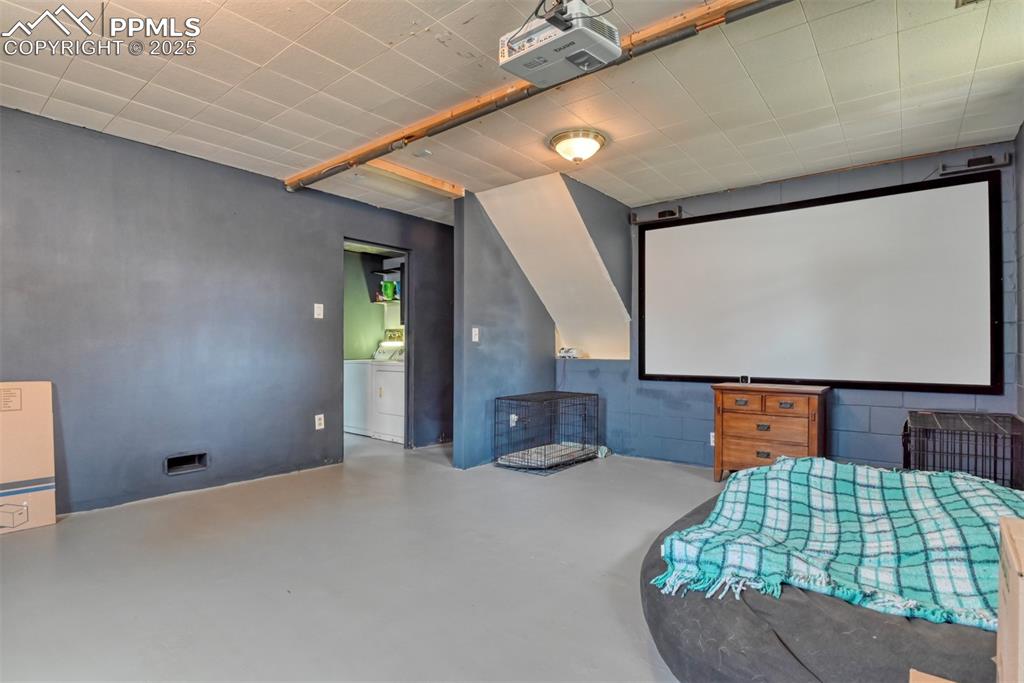 Image 17 of 37: Home theater room featuring finished concrete flooring and washer / dryer
