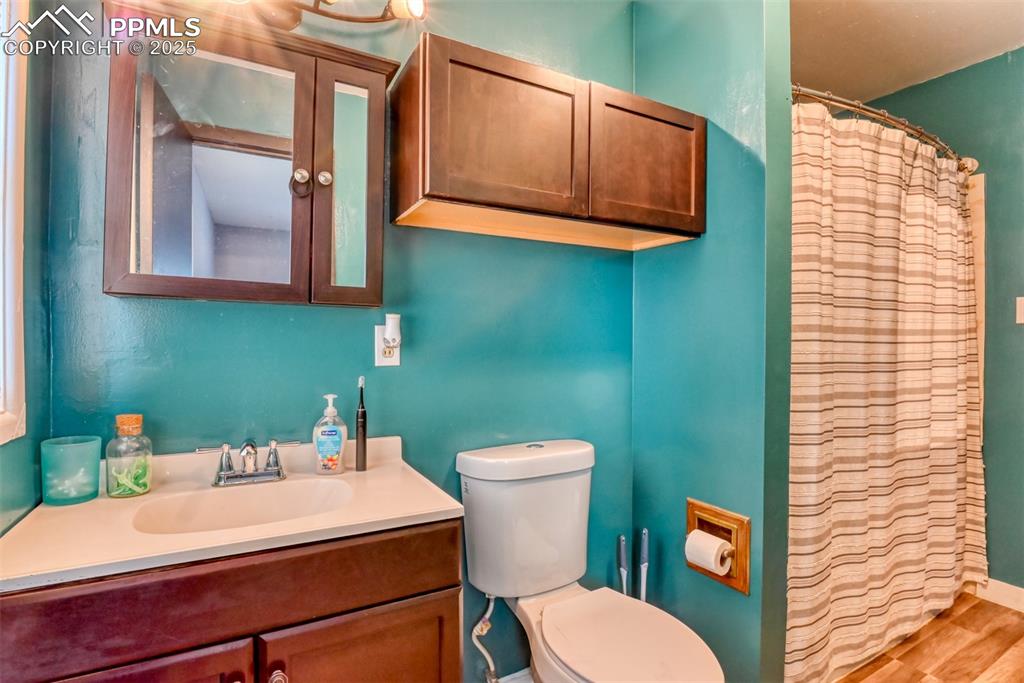 Image 26 of 37: Full bathroom featuring vanity, curtained shower, and wood finished floors