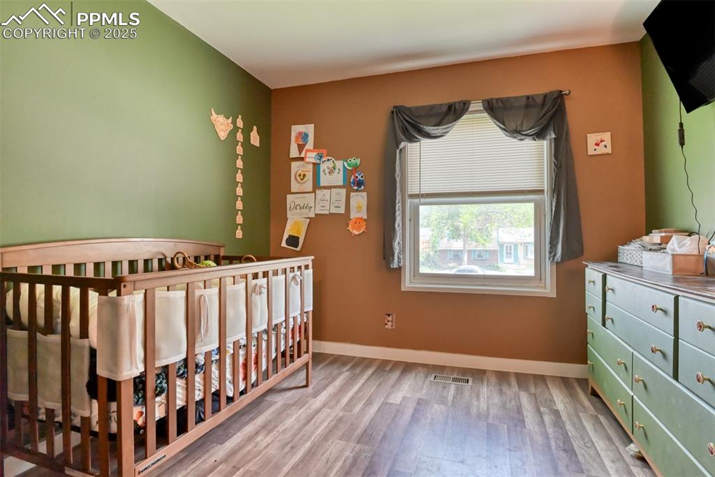 Image 31 of 37: Bedroom with wood finished floors and a crib