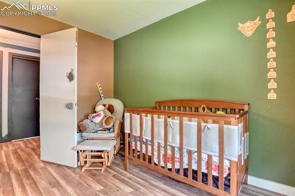 Image 33 of 37: Bedroom with wood finished floors and a nursery area
