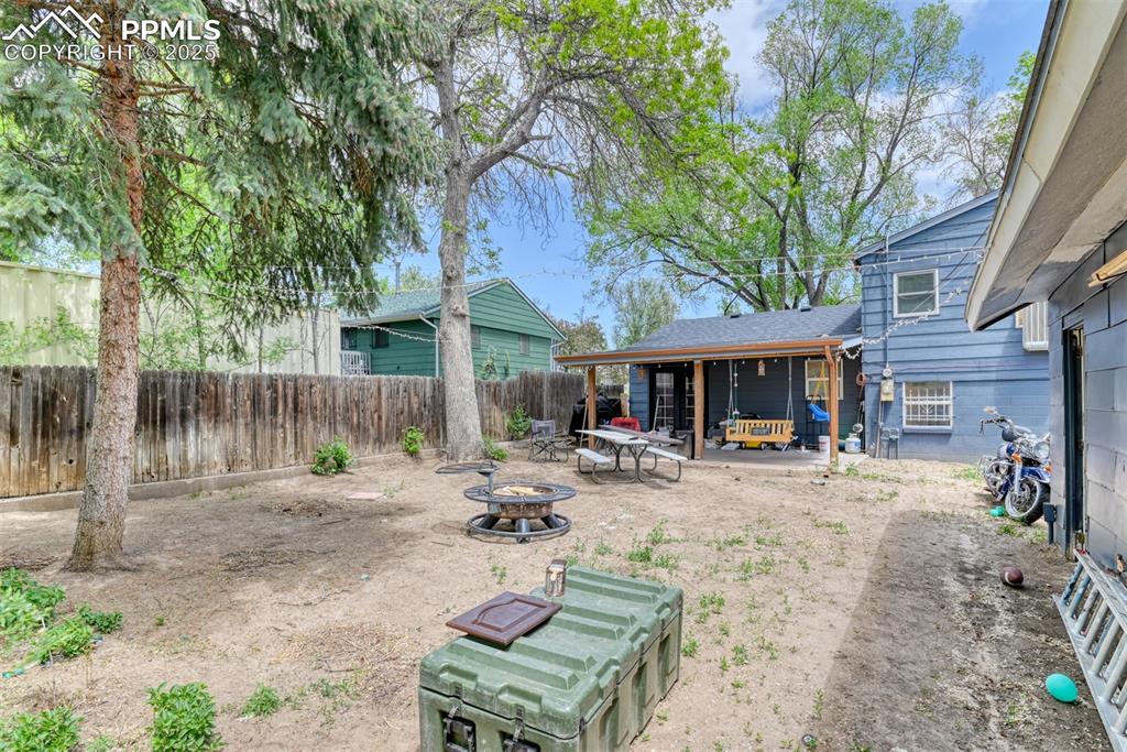 Image 8 of 37: Fenced backyard with an outdoor fire pit and a patio area