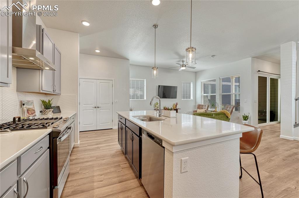 Image 13 of 50: Stainless steel appliances with a large undermount island sink and gas rang