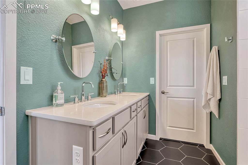 Image 25 of 50: The adjoining master bathroom features tile floors, dual vanities, large wa