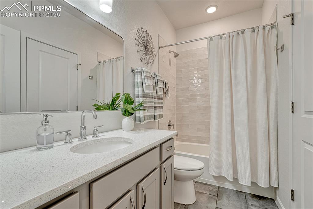 Image 33 of 50: The upper-level full bathroom has sparkling white quartz counters and a tex