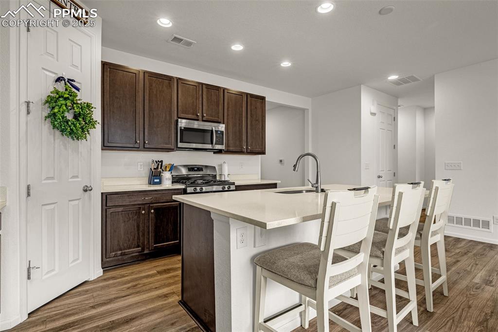 Image 13 of 37: Kitchen with dark brown cabinetry, recessed lighting, dark wood finished fl