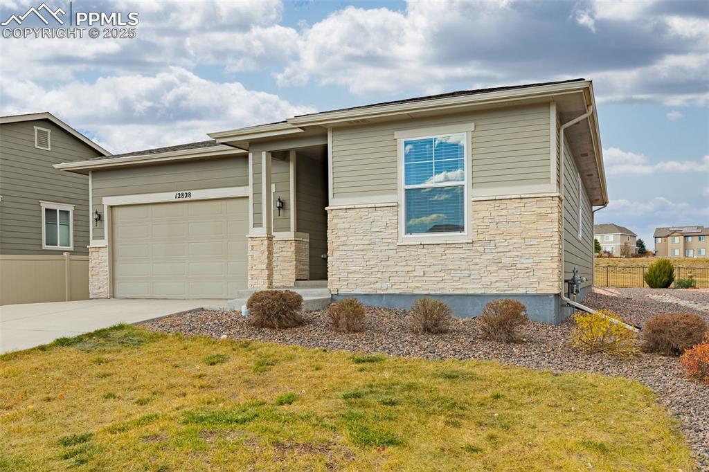 Image 36 of 37: Prairie-style home featuring stone siding, a garage, driveway, and a front 