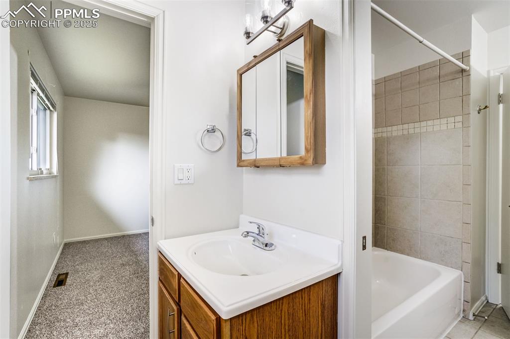 Image 18 of 44: Primary bath sink with tub in hallway full bath