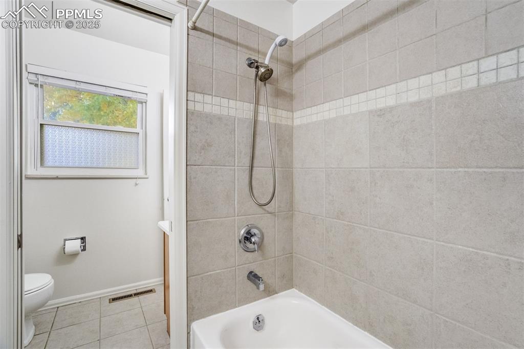 Image 20 of 44: Lovely tile surround in full hall bath tub area