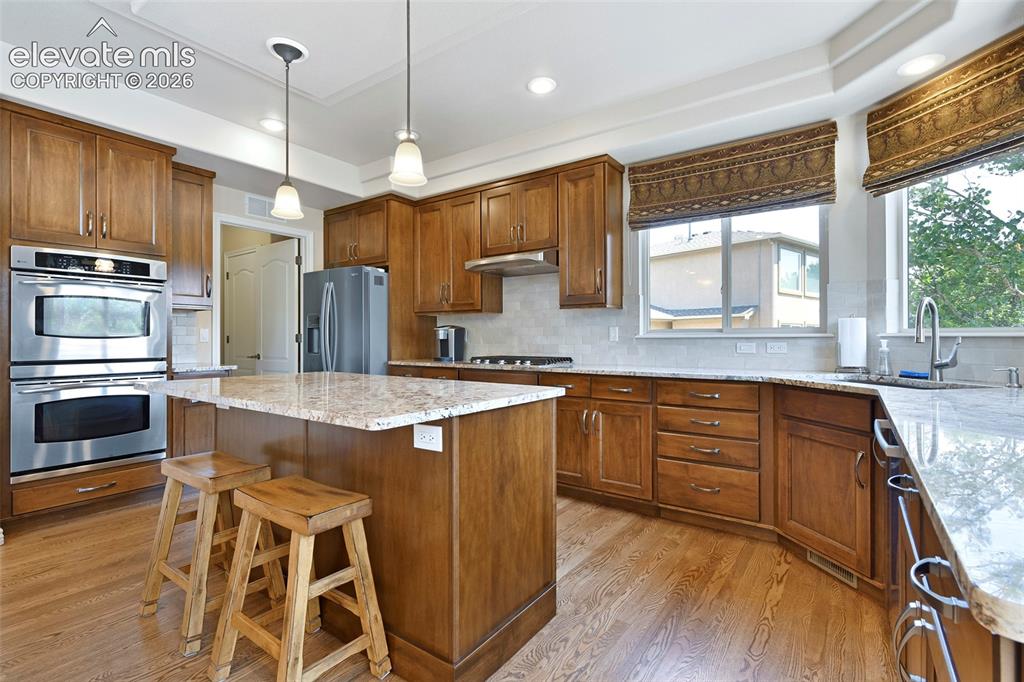 Image 14 of 46: Double Ovens, center island, granite counters and tile backsplash