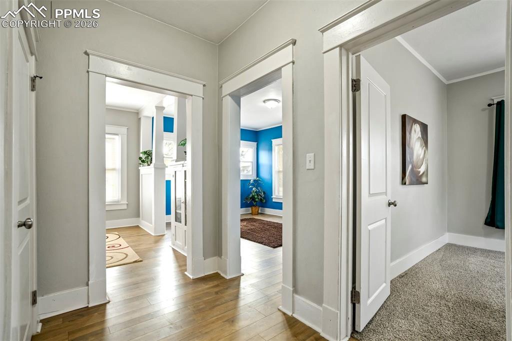 Image 19 of 38: Bright interior hallway with updated flooring and classic trim work, connec