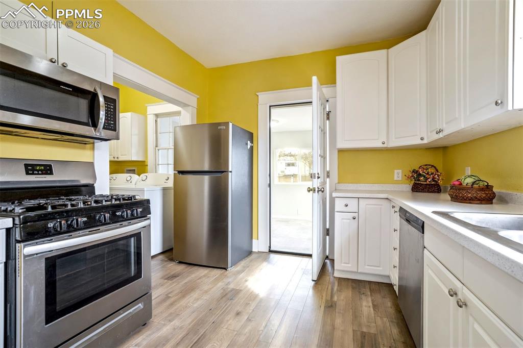 Image 21 of 38: Bright and cheerful kitchen featuring crisp white cabinetry, ample counter