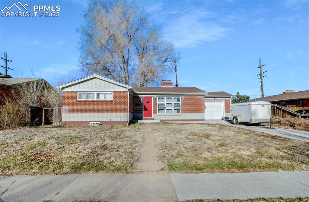 Caption: Ranch-style home with driveway, a chimney, an attached garage, and brick siding