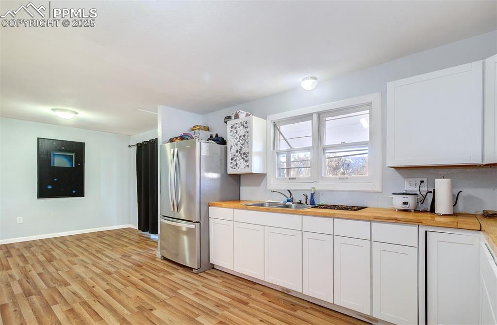 Image 11 of 29: Kitchen with wood counters, white cabinetry, a sink, light wood-style floor