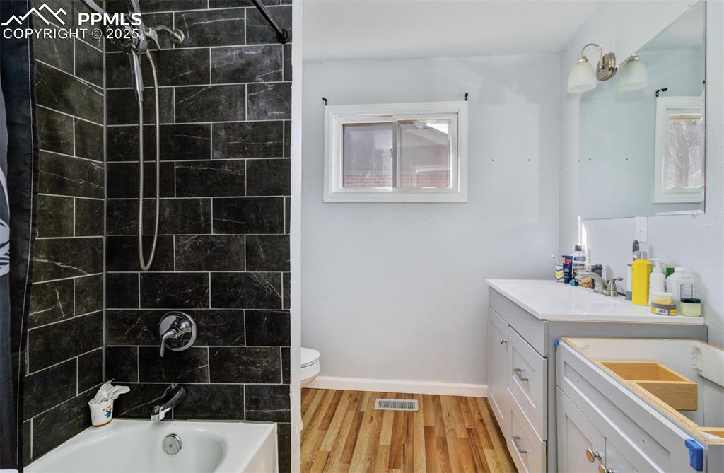 Image 15 of 29: Full bath with vanity, toilet, visible vents,  shower combination, and wood