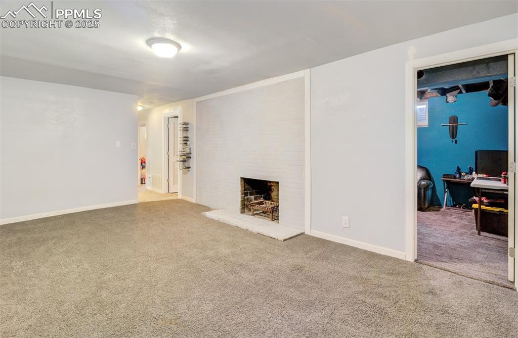 Image 19 of 29: Living room featuring baseboards, a fireplace, and carpet