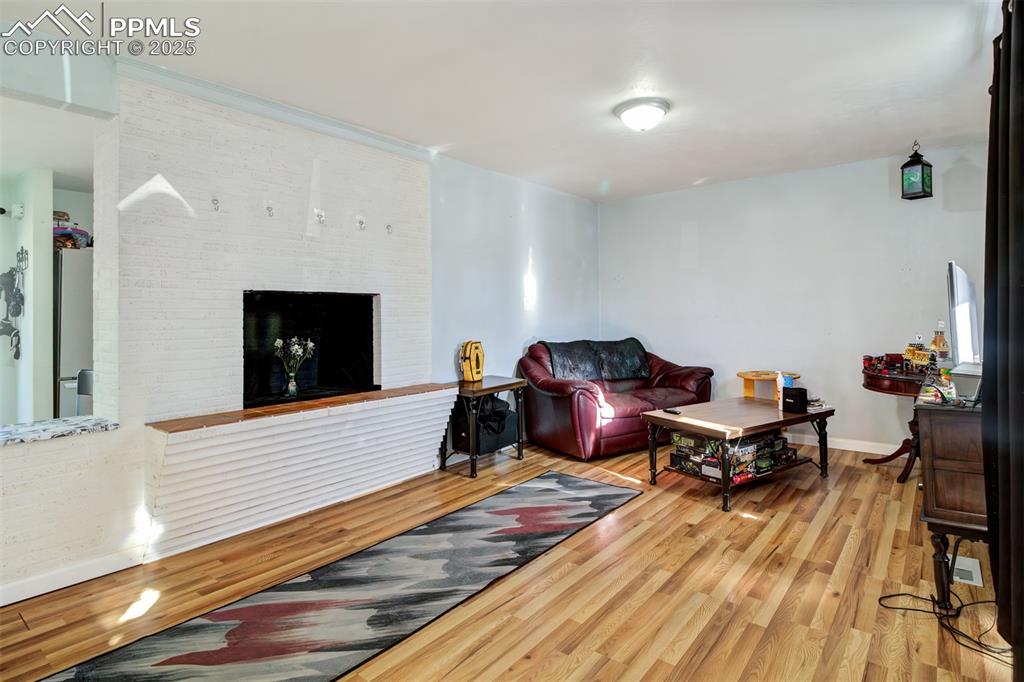 Image 2 of 29: Living room with baseboards, wood finished floors, and a brick fireplace