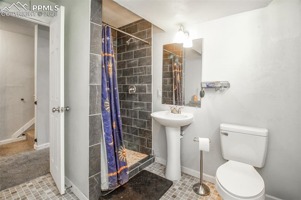 Image 24 of 29: Full bath featuring baseboards, a tile shower, toilet, and a sink