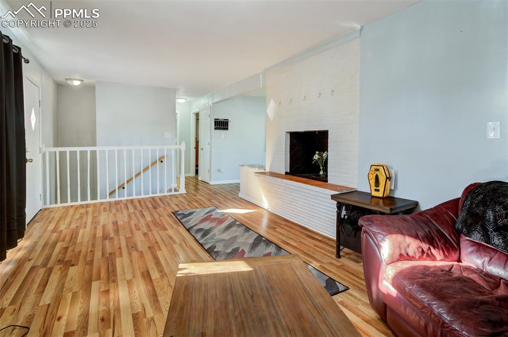 Image 4 of 29: Living room featuring a brick fireplace and light wood-type flooring