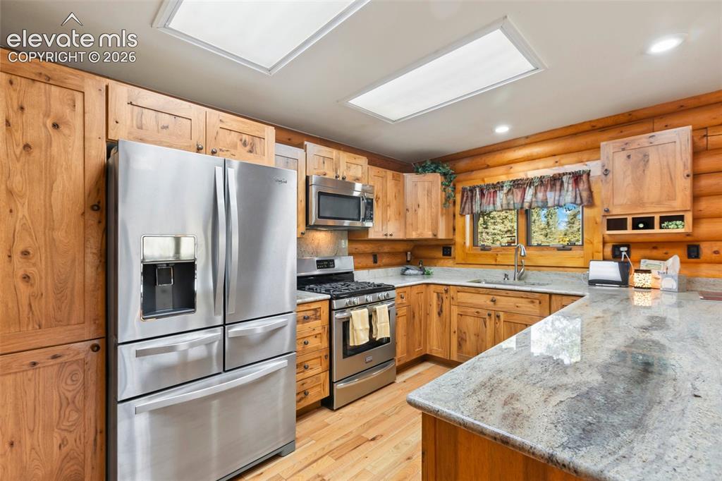 Image 15 of 37: Kitchen with white oak cabinets and granite counter top. All stainless stea