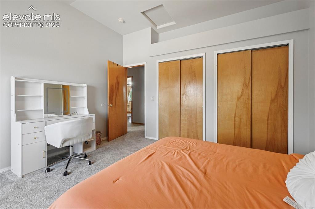 Image 13 of 37: Carpeted bedroom featuring two wood-finish sliding door closets, a single w