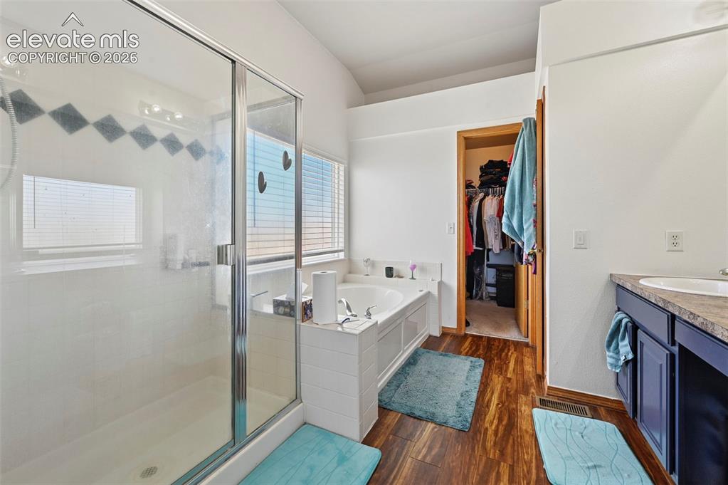 Image 16 of 37: Wood-finish flooring throughout, featuring a glass-enclosed shower, built-i