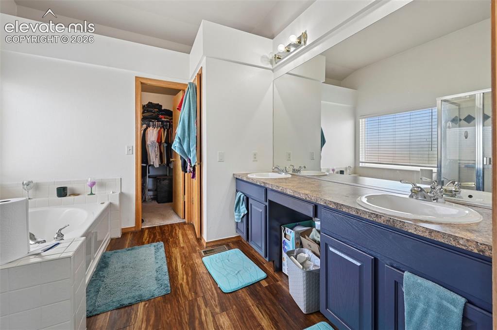 Image 17 of 37: Bathroom featuring wood-finish flooring, a built-in tub with white tile sur