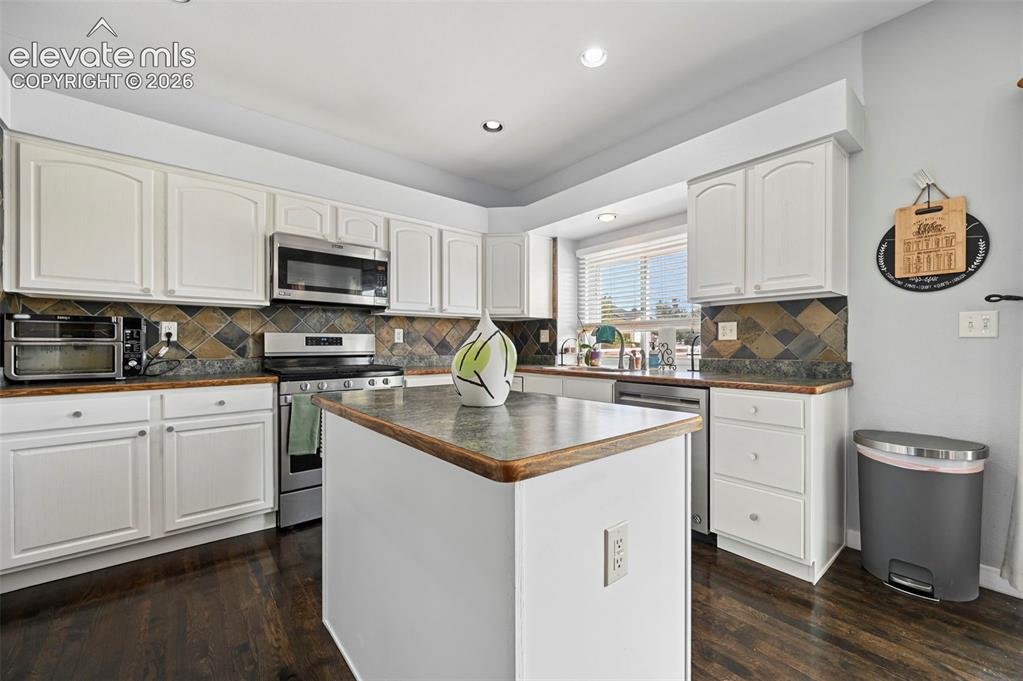 Image 2 of 37: Kitchen featuring white cabinetry, stainless steel appliances, a central is