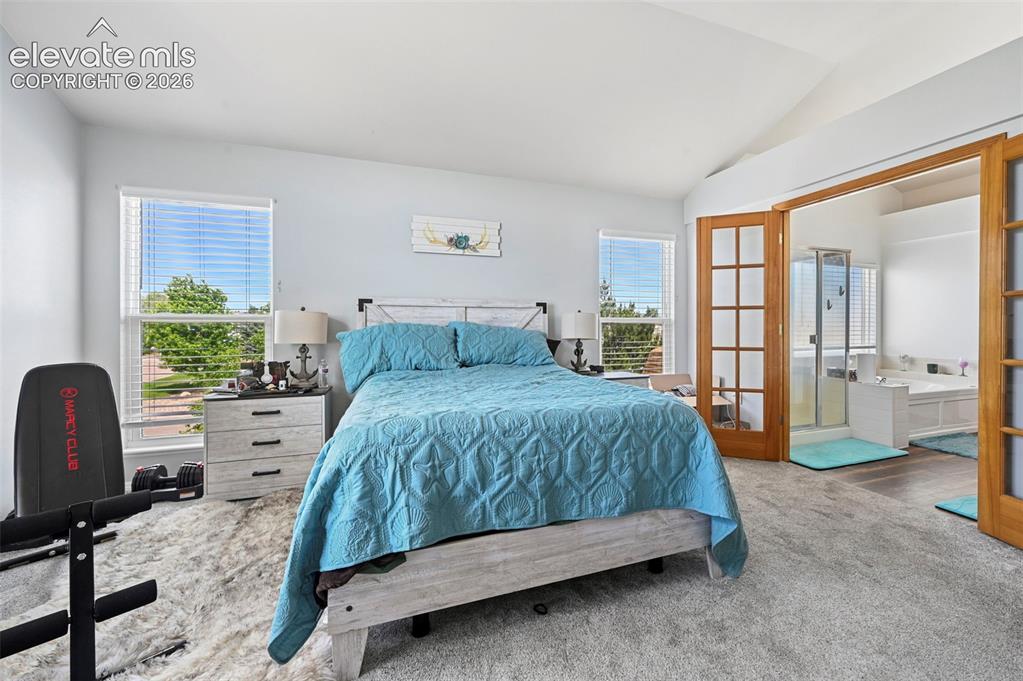 Image 20 of 37: Spacious bedroom featuring vaulted ceilings, two large windows with horizon