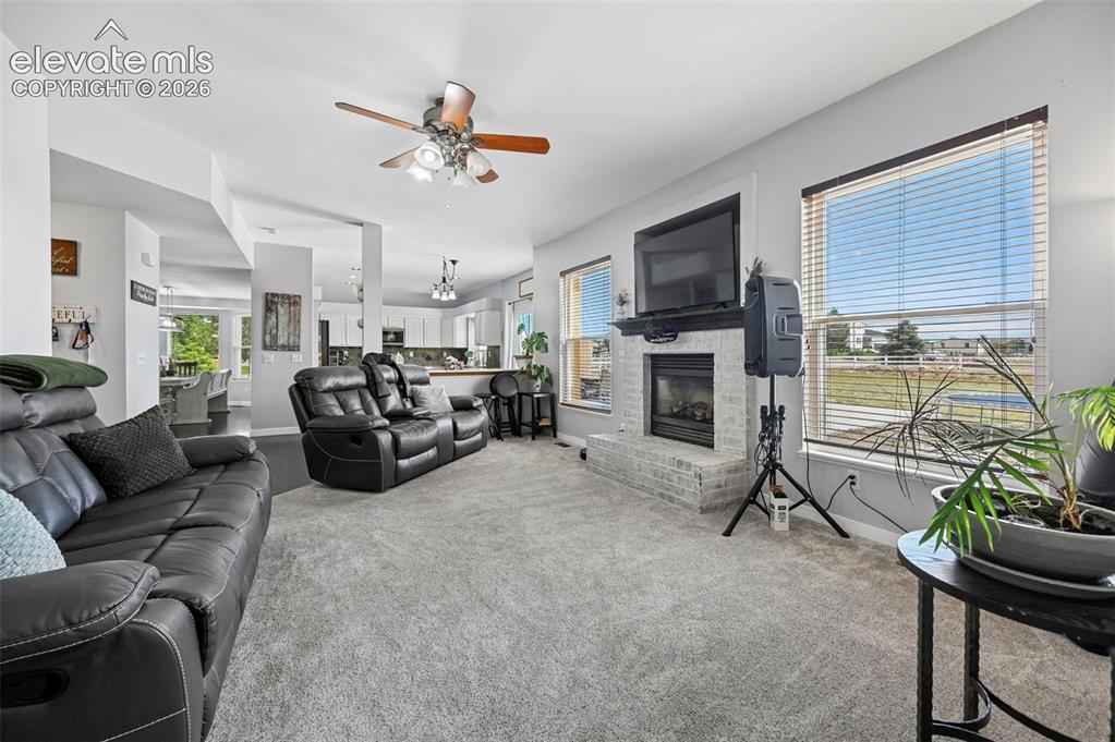 Image 22 of 37: Living area featuring light gray carpeting and a white brick fireplace with