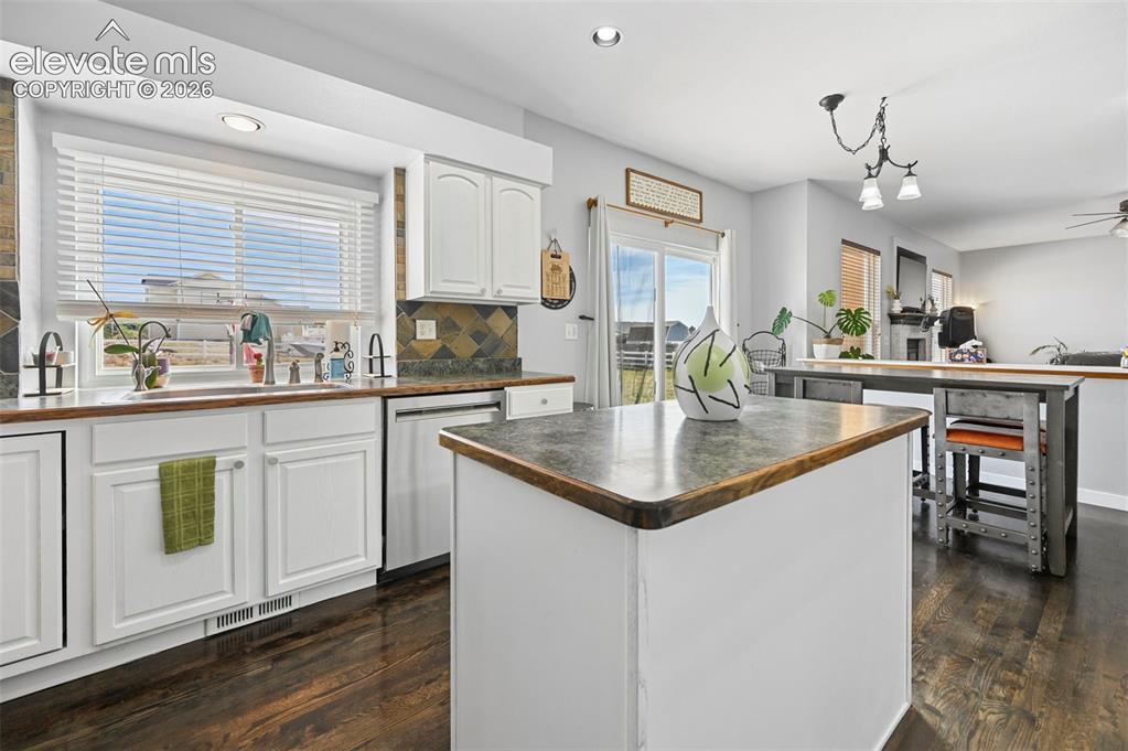 Image 23 of 37: Kitchen featuring white cabinetry, dark wood-finish flooring, a central isl