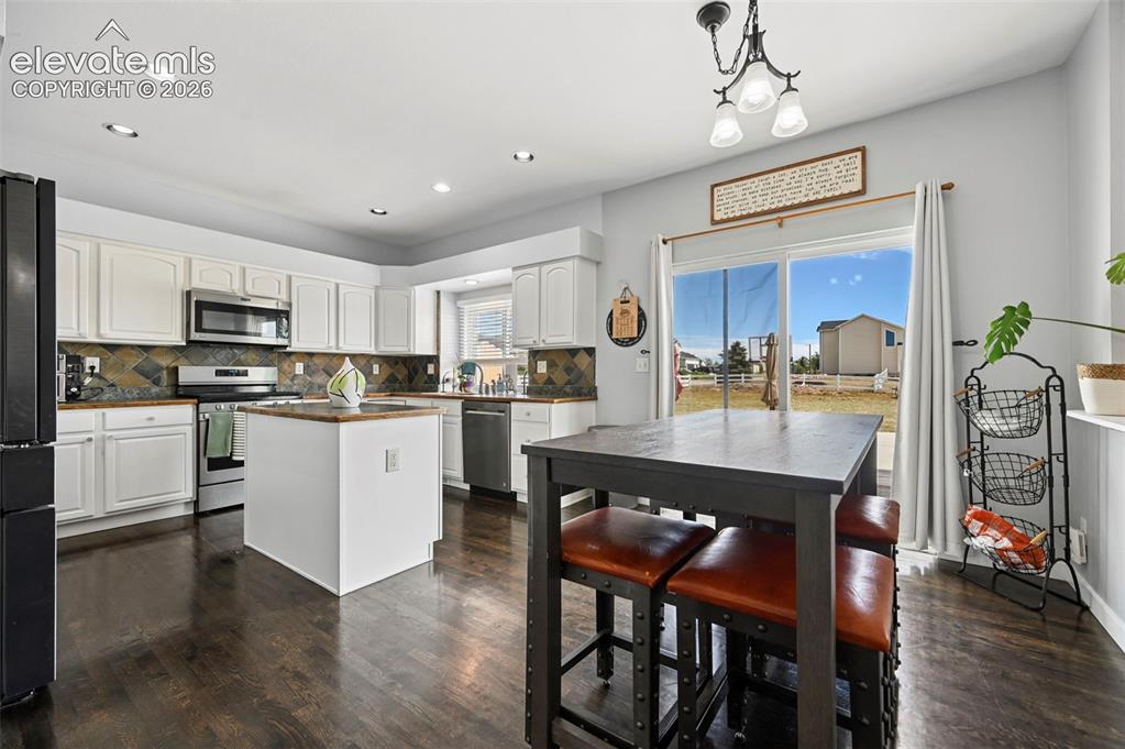 Image 26 of 37: Modern kitchen featuring dark wood-finish flooring, white cabinetry, and a